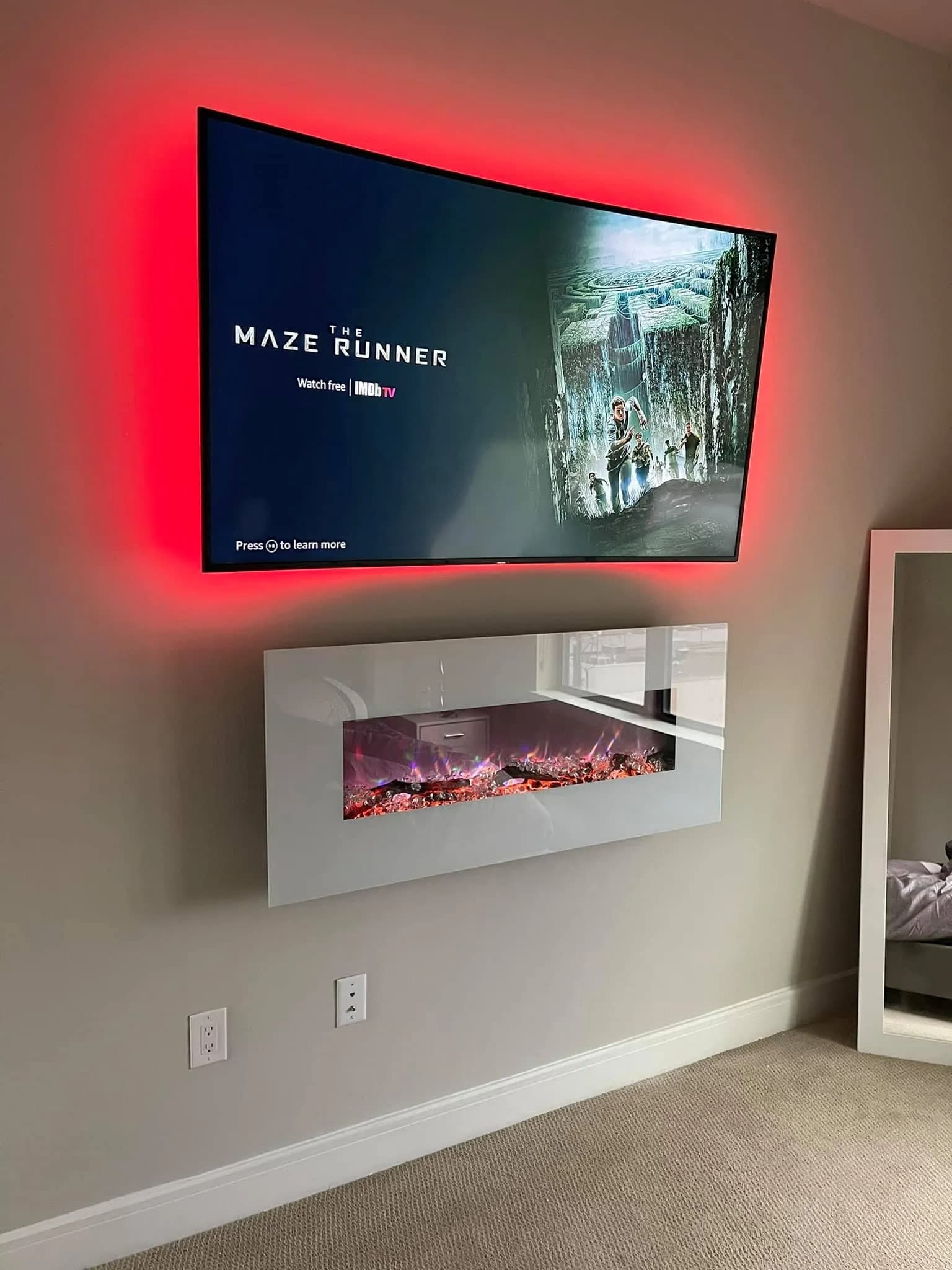 TV mounted above electric fireplace with red LED backlight