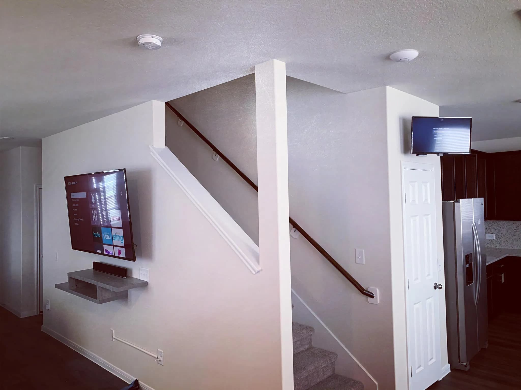 TV mounted near staircase with floating shelf below