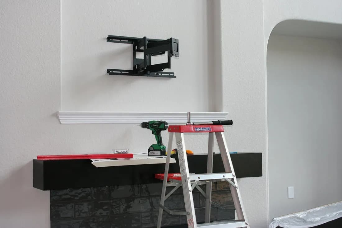 Technician installing full-motion TV bracket — work in progress